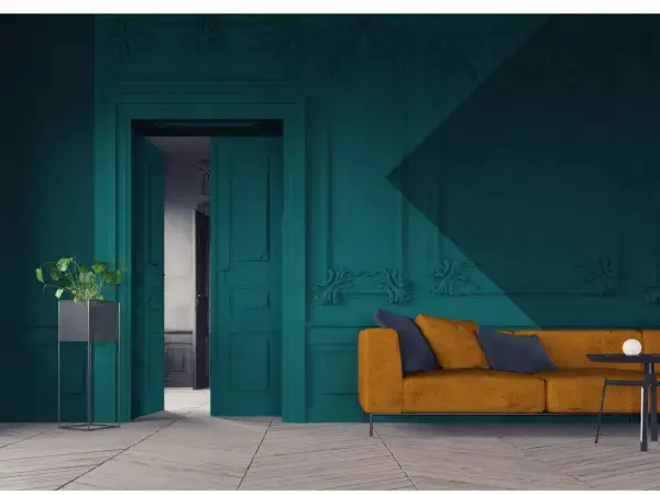Een modern interieur waar groen en blauw combineren. Een okergele bank met donkerblauwe kussens staat voor een diepblauwe muur met sierlijke ornamenten.