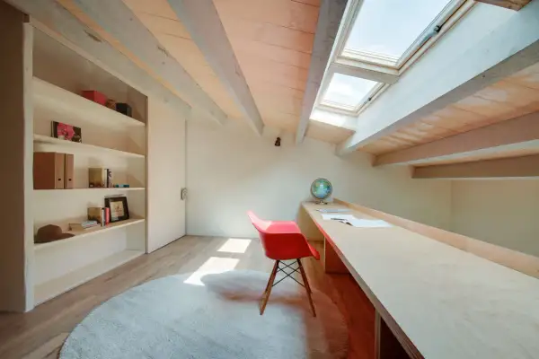 Een opgeruimde zolder met een bureau, boekenkast en dakramen. Perfect voor een rustige werkplek.
