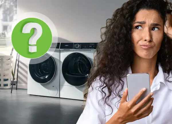 Vrouw met telefoon kijkt gefrustreerd naar wasmachine. Is er te weinig was in wasmachine?